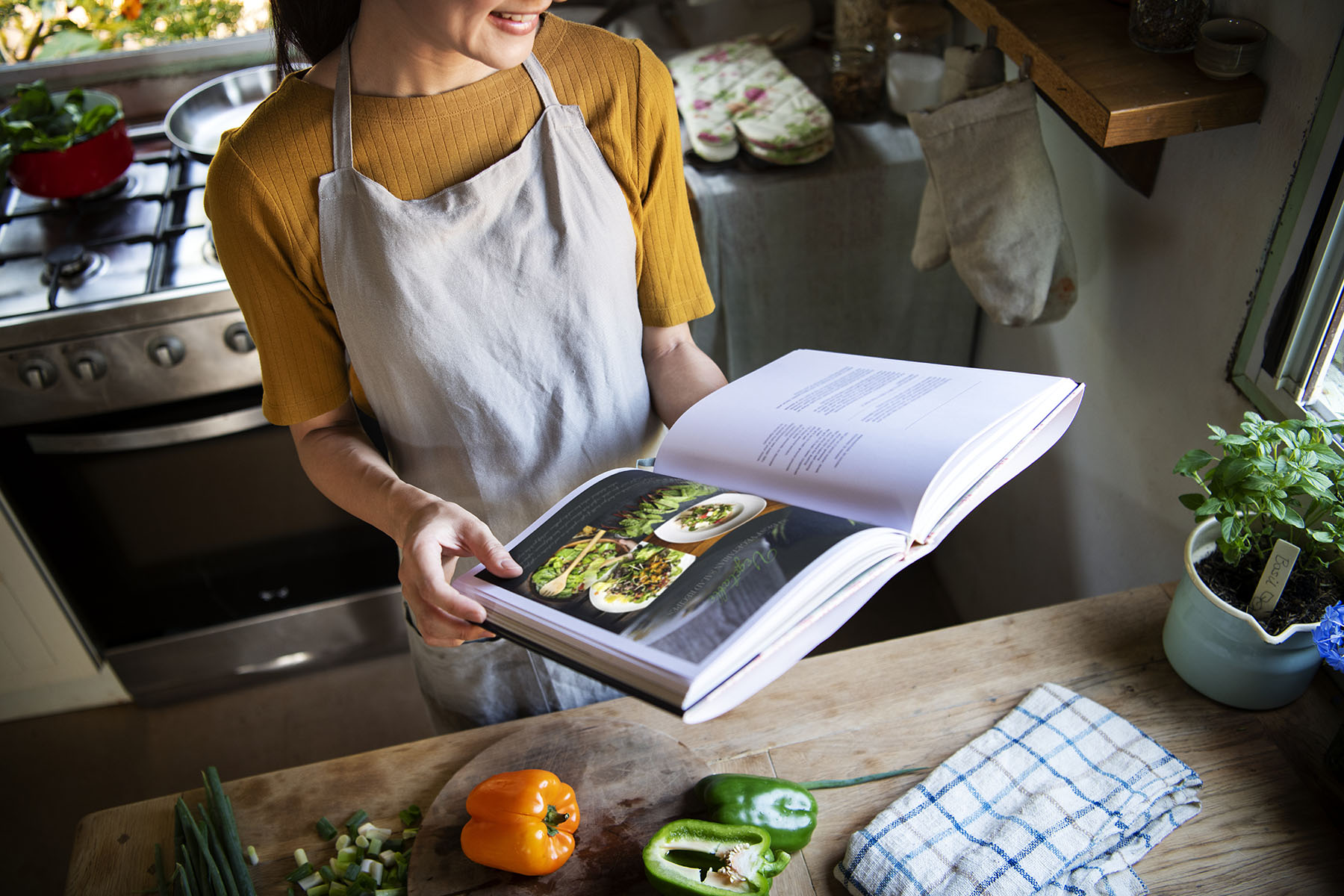 Happy woman reading a cookbook in the kitchen